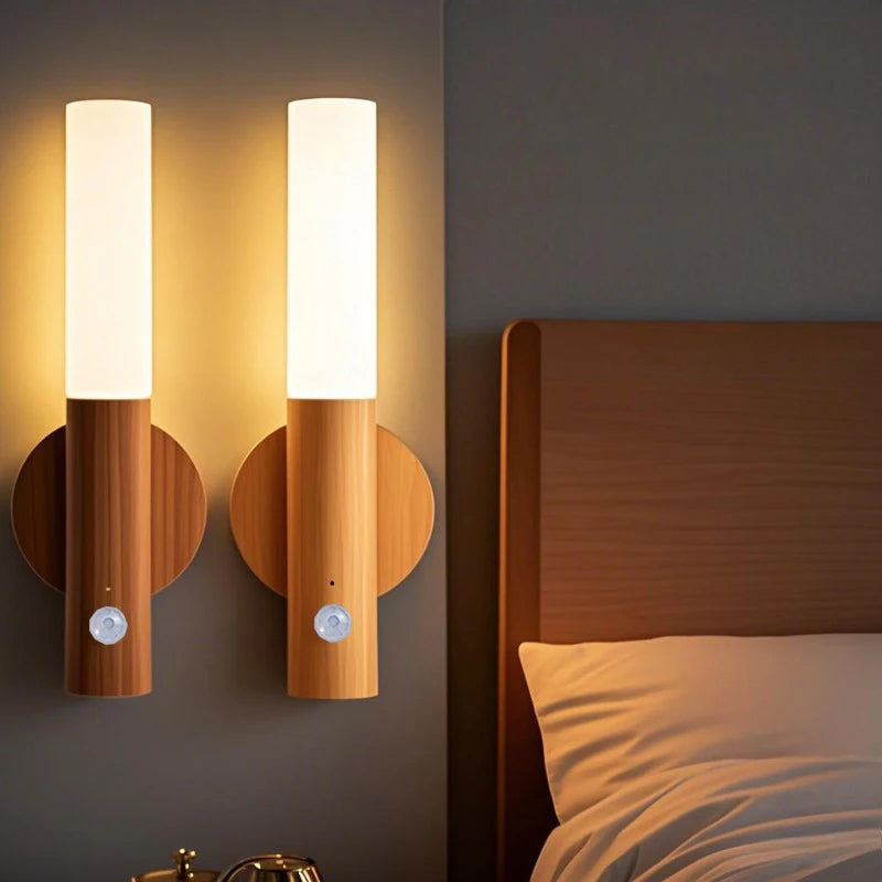 Two wooden wall sconces on a dark wall next to a bed.